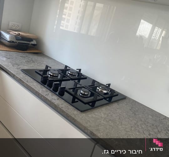 כיריים גז שחורות על משטח מטבח אפור